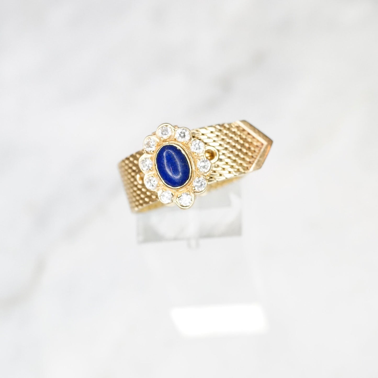 14K yellow gold vintage adjustable mesh belt buckle ring featuring an oval lapis lazuli cabochon surrounded by diamond accents, creating a floral motif at the center.