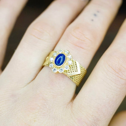 Vintage 14K yellow gold mesh belt buckle ring with lapis lazuli cabochon center stone surrounded by diamond accents on an adjustable band, stamped "VCA NY 14K", shown on a hand.