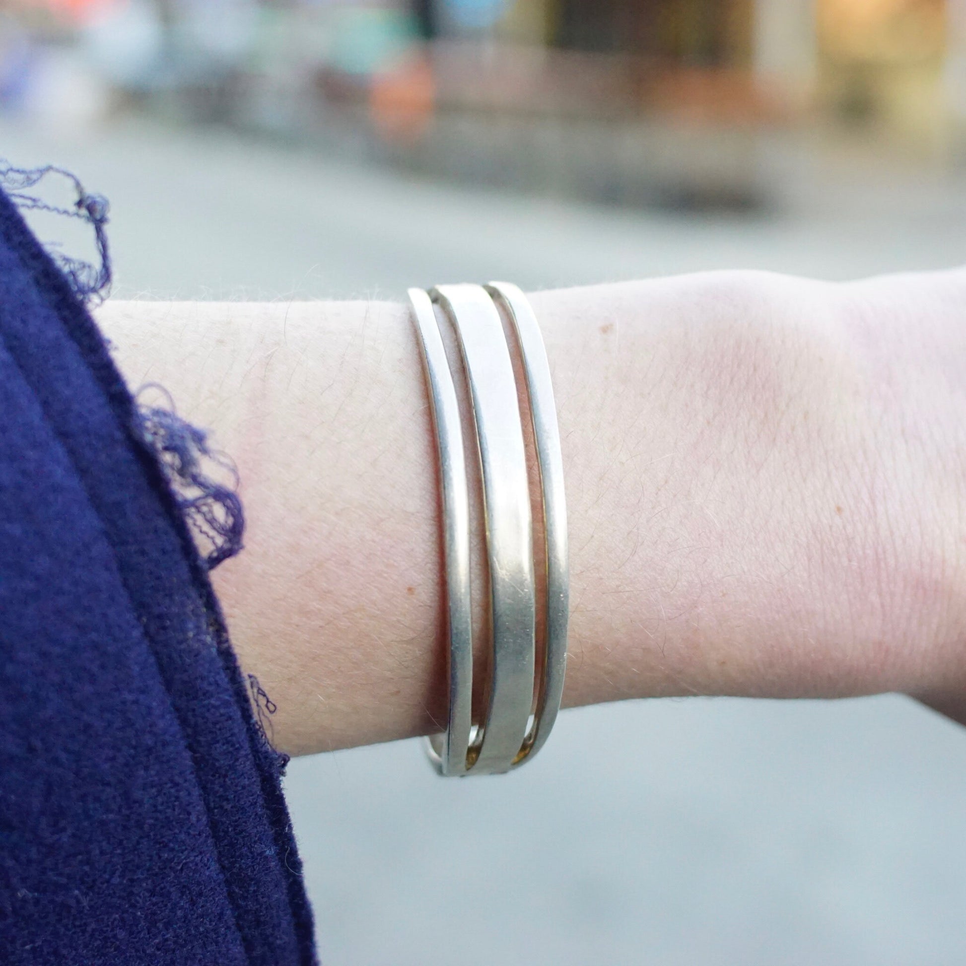 Vintage sterling silver cut out hinged bangle bracelet on woman's wrist, close-up view. Modernist design TAXCO Mexico 925 silver bracelet with open cut-outs, approximately 6 1/2 inches long.