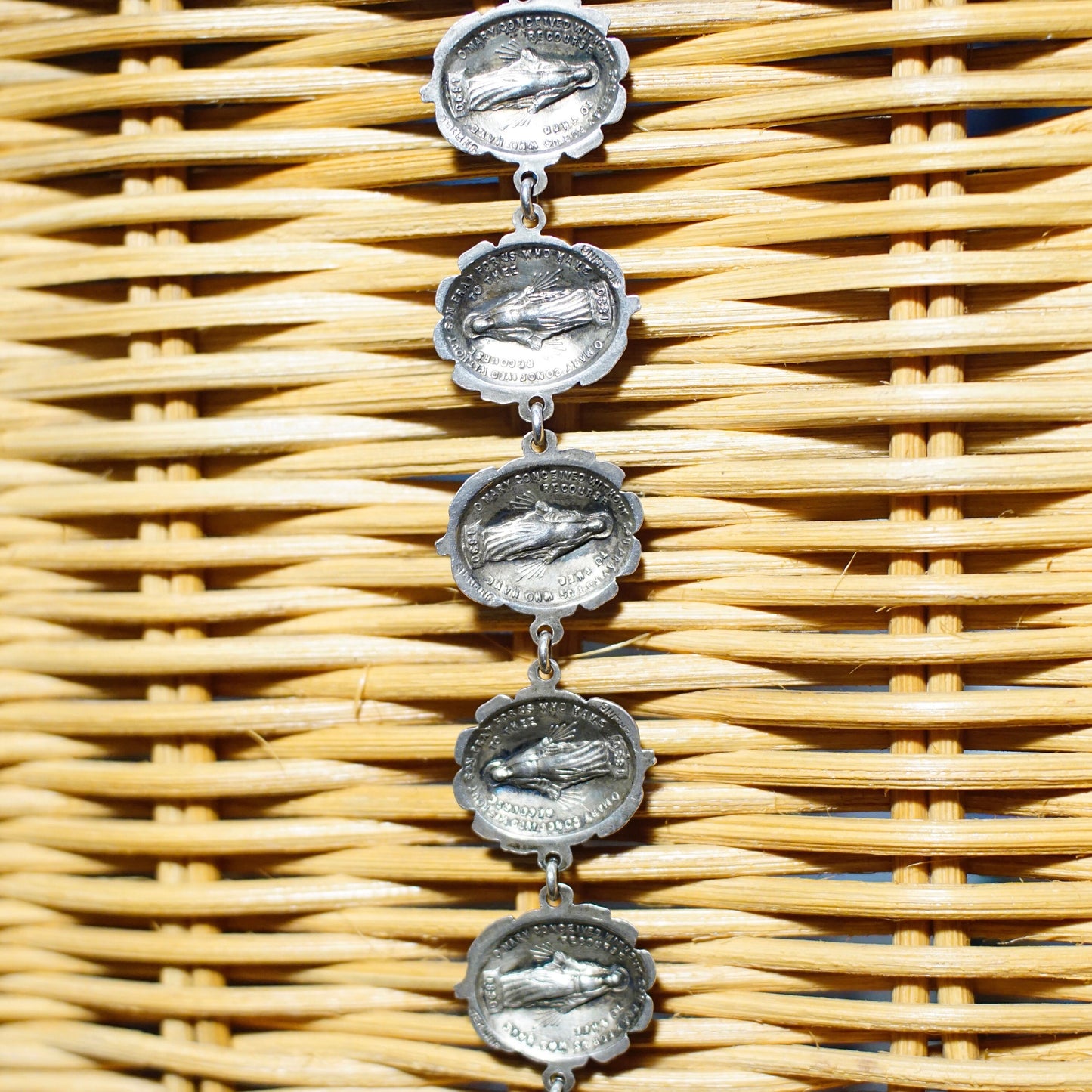 Vintage HMH sterling silver reversible bracelet featuring rosebud and Mother Mary medallions linked together on a woven rattan background.