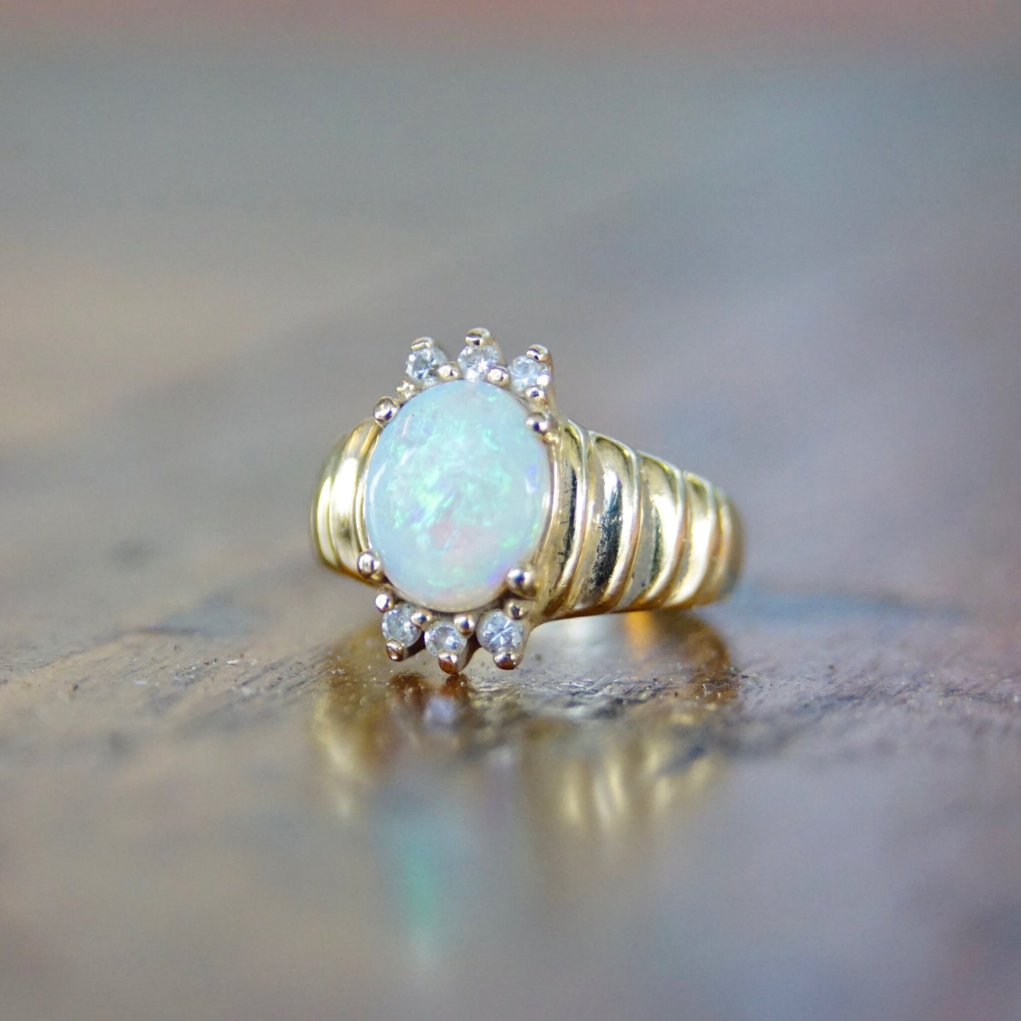 Vintage 14K gold cocktail ring featuring a beautiful oval opal center stone accented by round brilliant-cut diamonds on a graduated yellow gold band, ring size 6 1/4 US.