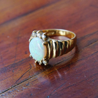 Vintage 14K gold opal and diamond cocktail ring featuring a beautiful oval opal stone accented by small diamonds set in a graduated yellow gold band, ring size 6 1/4 US.