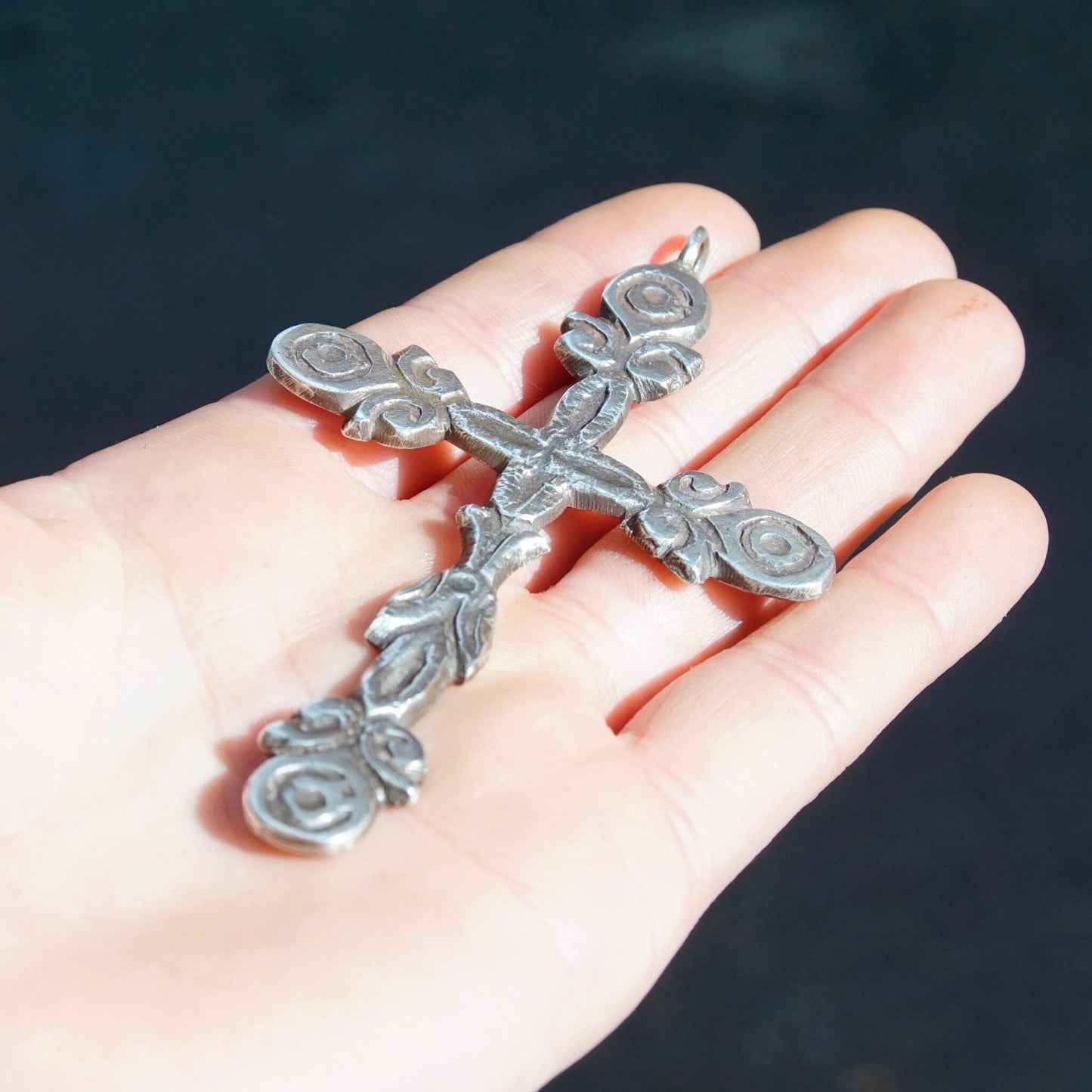 Vintage large sterling silver gothic cross pendant held in palm of hand, showing ornate hammered oxidized silver design. The ornate cross is approximately 4 inches long.