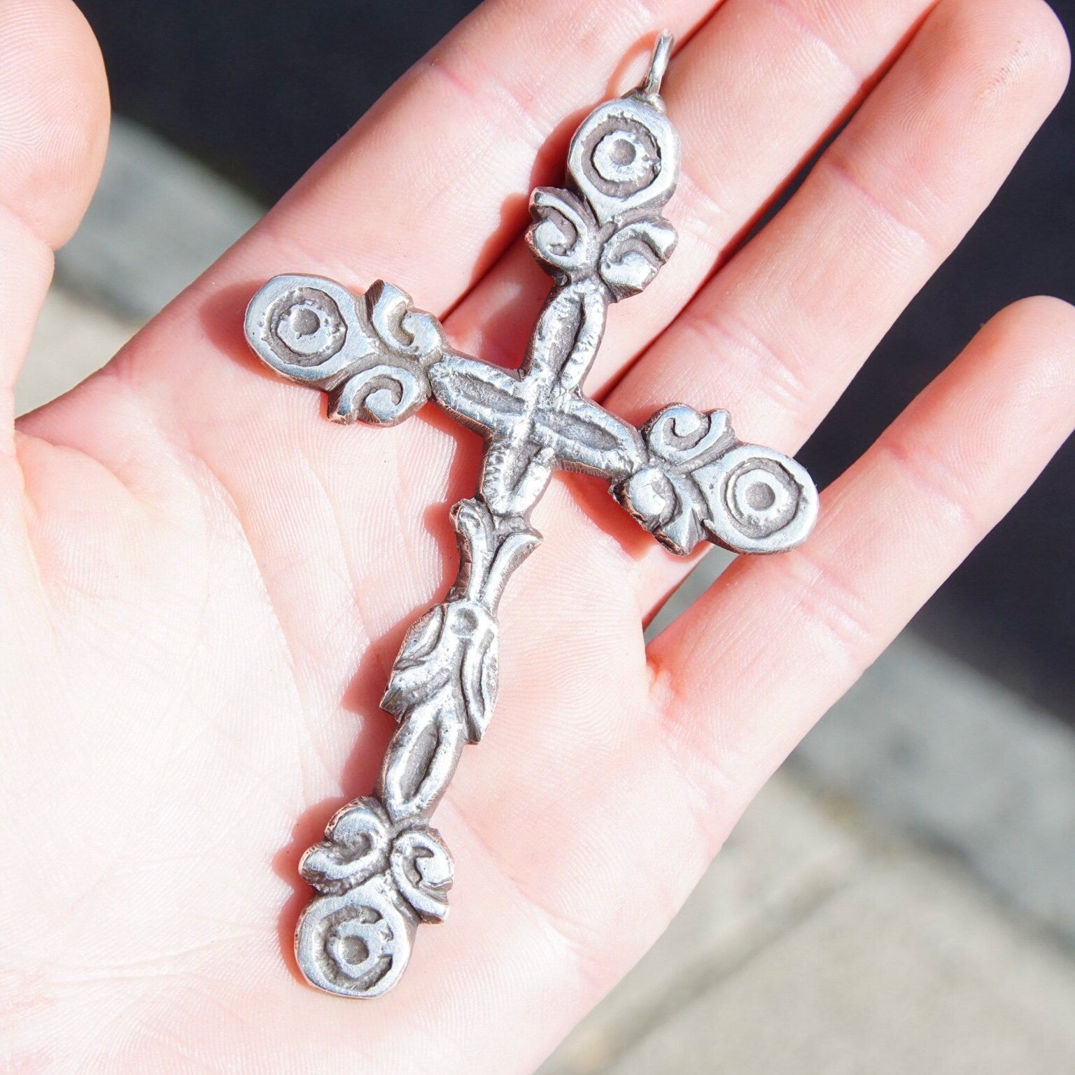 Ornate sterling silver Gothic cross pendant held in palm of hand, featuring intricate hammered silver design with oxidized accents, approximately 4 inches long, 925 silver vintage jewelry.