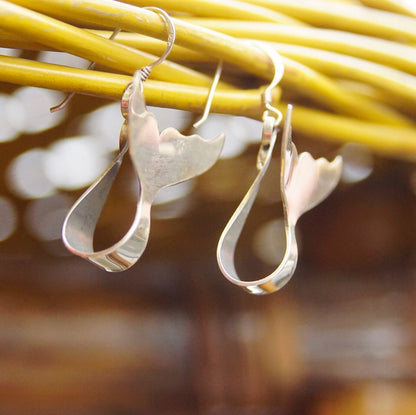 Vintage sterling silver whale tail dangle earrings hanging from thin yellow cord, minimalist aquatic jewelry design