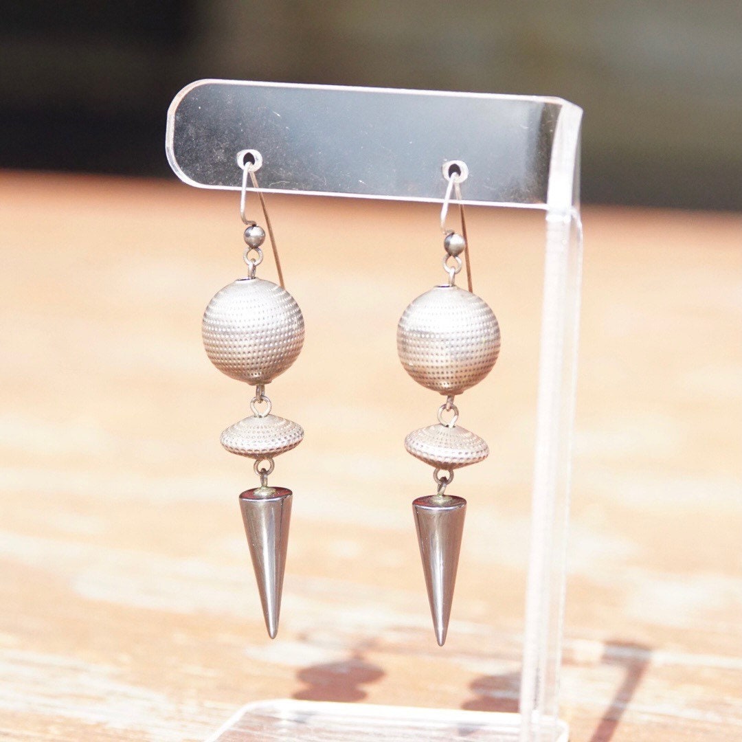 Vintage modernist silver ball and hematite spike dangle earrings displayed on clear plastic stand