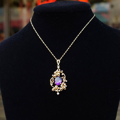 14K gold vintage pendant necklace with faceted amethyst center stone surrounded by ornate diamond-studded frame, choker style chain 14 3/4 inches long, displayed on black velvet bust.