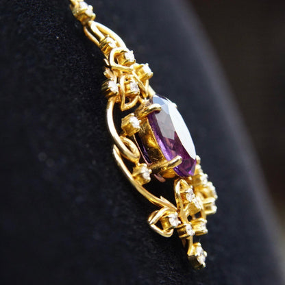 Vintage 14K gold pendant necklace featuring an ornate diamond-accented frame surrounding a faceted amethyst stone, suspended from a delicate gold chain choker measuring 14 3/4 inches in length.