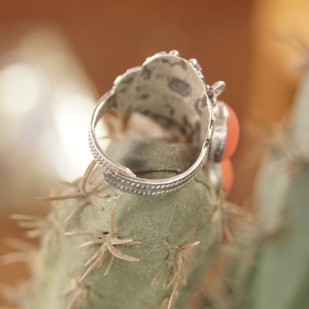 Vintage sterling silver filigree tassel ring from Taxco, Mexico with dangling red and orange beads, adjustable band, close-up view against blurred background