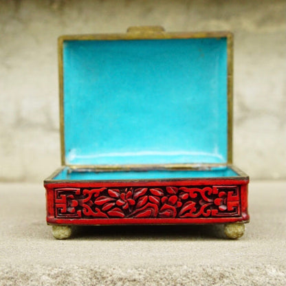 Antique Chinese carved cinnabar enamel box with intricate floral and fauna motifs, featuring a hinged lid and vibrant red and turquoise colors, measuring 4 inches wide, 3.5 inches deep and 2 inches high.