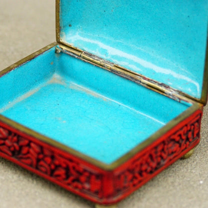 Antique Chinese carved cinnabar enamel box with intricate floral and landscape motifs, featuring a hinged lid and vibrant turquoise interior, measuring 4 inches wide, 3.5 inches deep and 2 inches high.