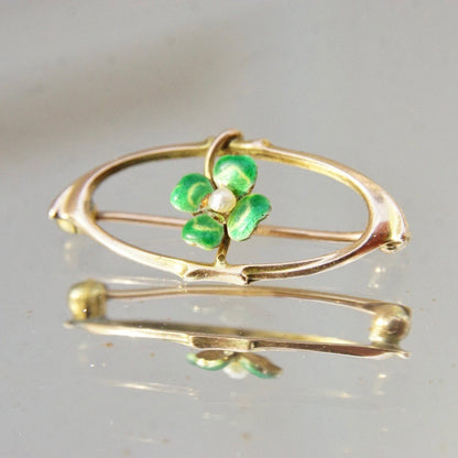 Vintage 10K gold brooch pin featuring a green enamel four-leaf clover design accented with a tiny seed pearl, measuring approximately 1 1/8 inches long, in the Art Nouveau style.