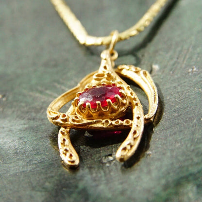 Vintage 14K yellow gold wishbone heart pendant necklace featuring a faceted red ruby, on a delicate 2mm flat gold chain, measuring 20.5 inches in length.