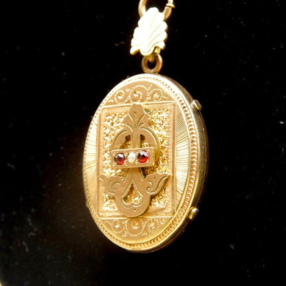 Antique Victorian gold filled locket pendant necklace with intricate etched cameo design, garnet and diamond accents, on a thick gold chain. Mourning jewelry from the 1800s.