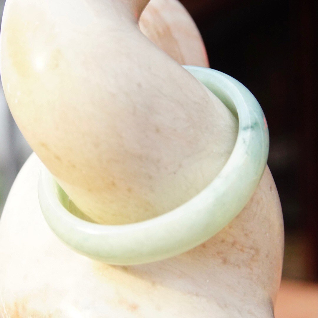 Vintage mid-century solid light green marbled jade bangle bracelet, 54 grams, 7 inches long, shown on a person's arm.