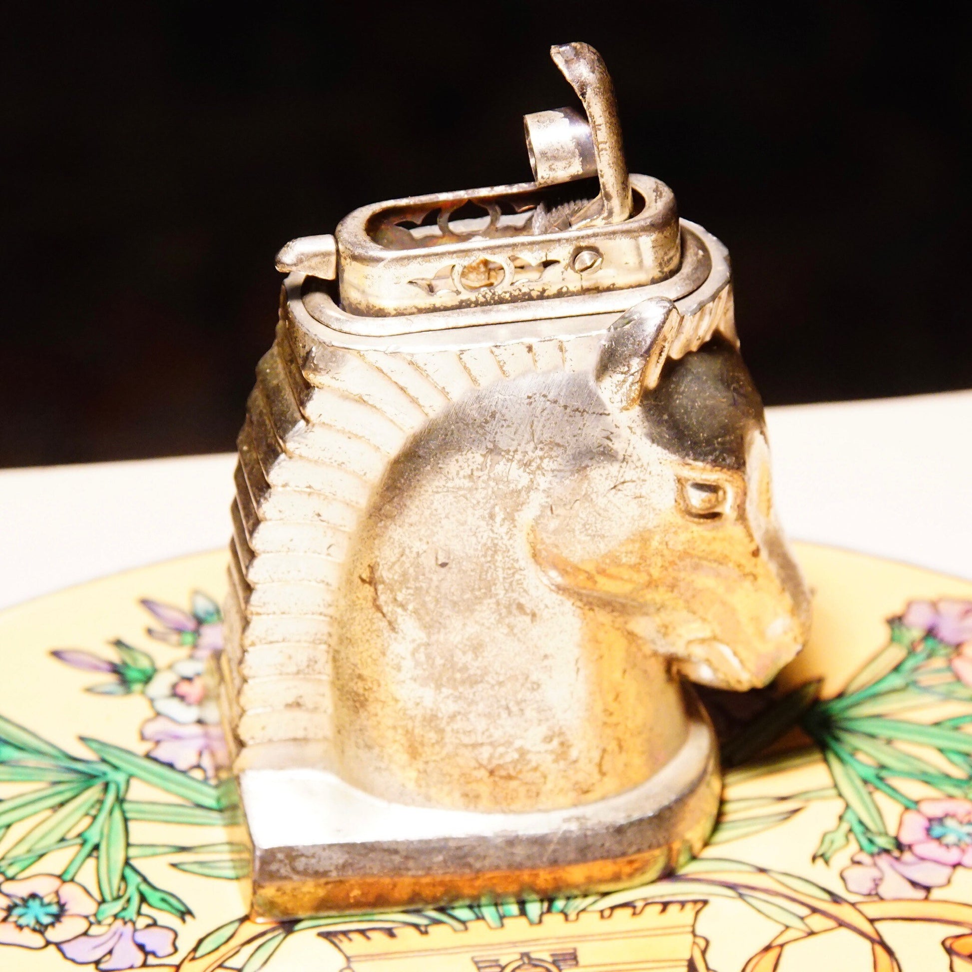 Vintage silver-plated horse head table lighter made in Occupied Japan, untested collectible butane lighter measuring 2 3/4 inches tall, displayed on floral patterned surface.