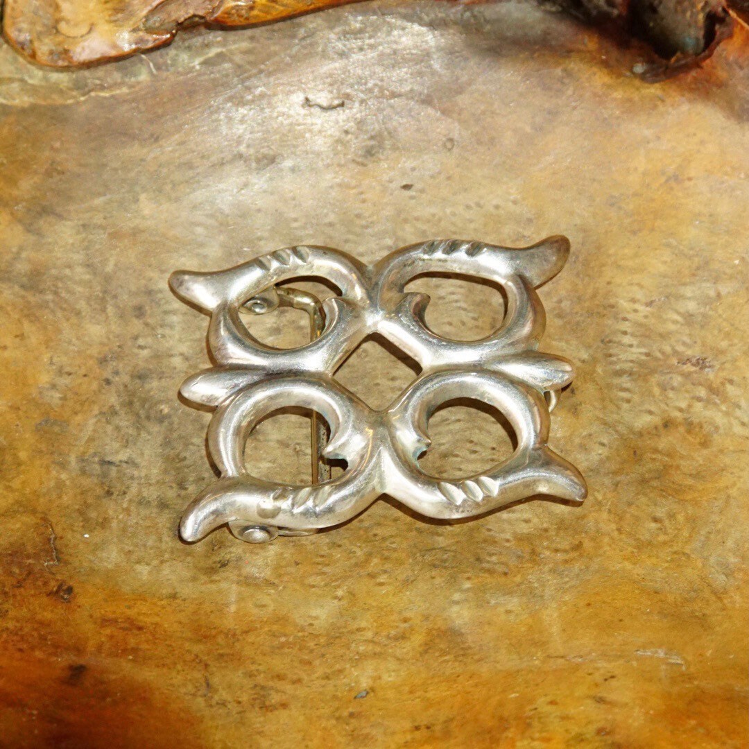 Vintage Navajo sand cast sterling silver concho belt buckle with intricate design on weathered leather background