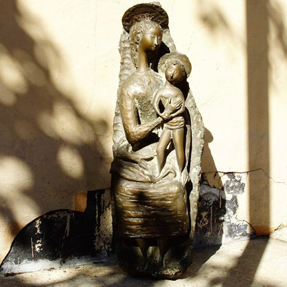 Vintage Italian bronze sculpture depicting an abstract, stylized representation of the Virgin Mary tenderly holding the infant Jesus, created by artist Toni Furlan. The statue has an antique patina and measures approximately 36 inches tall.