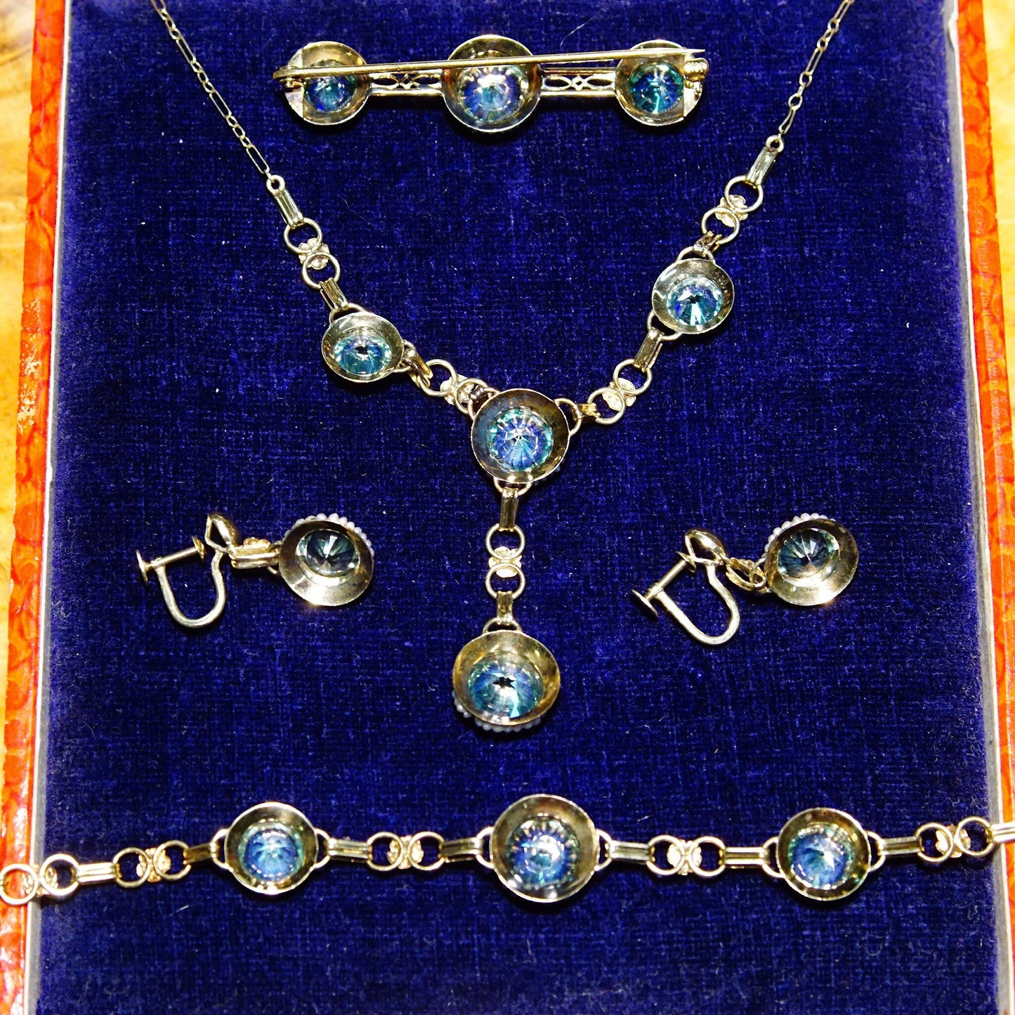 Antique 14K yellow gold aquamarine and seed pearl jewelry set including Y-necklace, bracelet, screw back earrings and brooch featuring brilliant blue aquamarine stones accented by small white seed pearls, displayed in velvet-lined case.