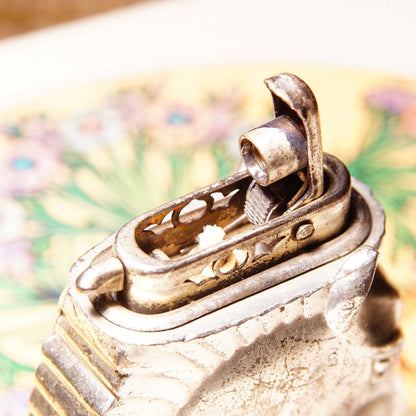 Vintage silver-plated horse head table lighter made in Occupied Japan, collectible butane lighter measuring 2 3/4 inches, untested condition, close-up view of intricate equestrian-themed lighter against colorful floral background.