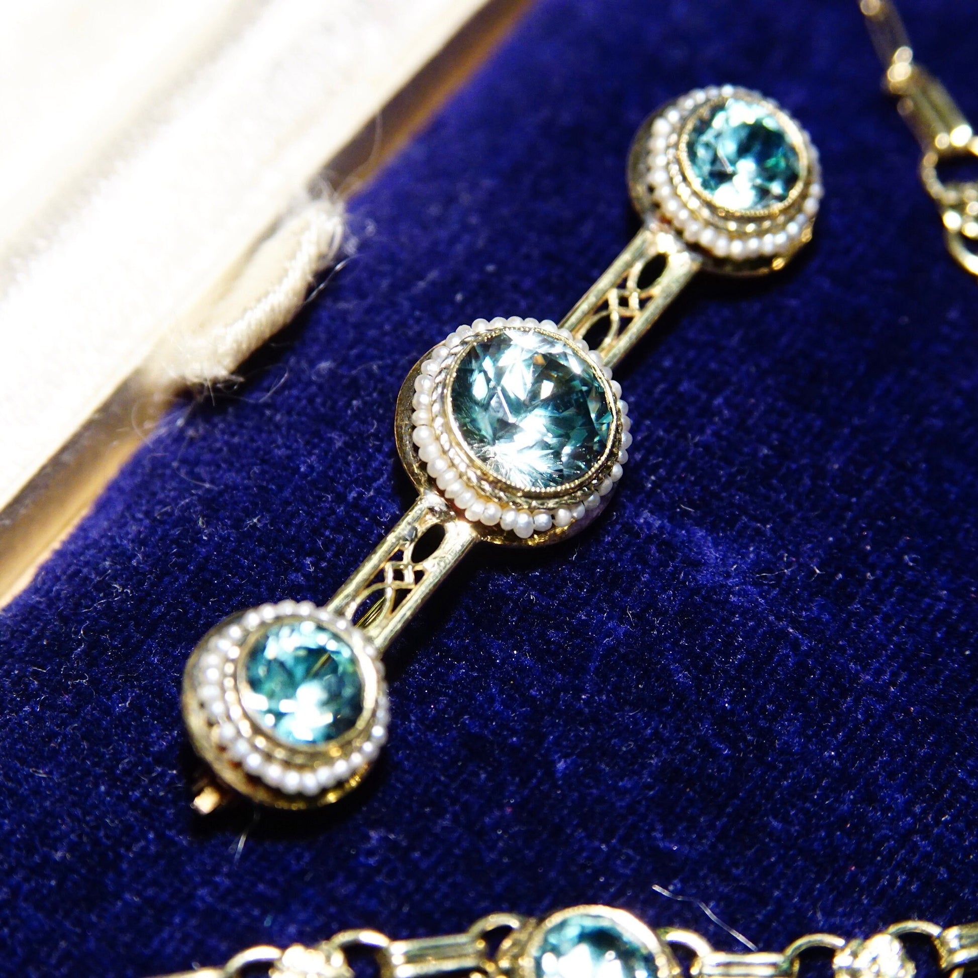 Vintage 14K gold aquamarine pearl seed jewelry set featuring brilliant blue stones in a matching Y-pendant necklace, bracelet, screw back earrings and brooch displayed on a blue velvet background.