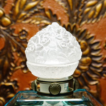 Alt text: Antique 1920s Austrian perfume bottle with frosted glass figural dauber and intricately carved glass stopper, featuring pewter mounts, measuring 8 inches tall, displayed against an ornate background.