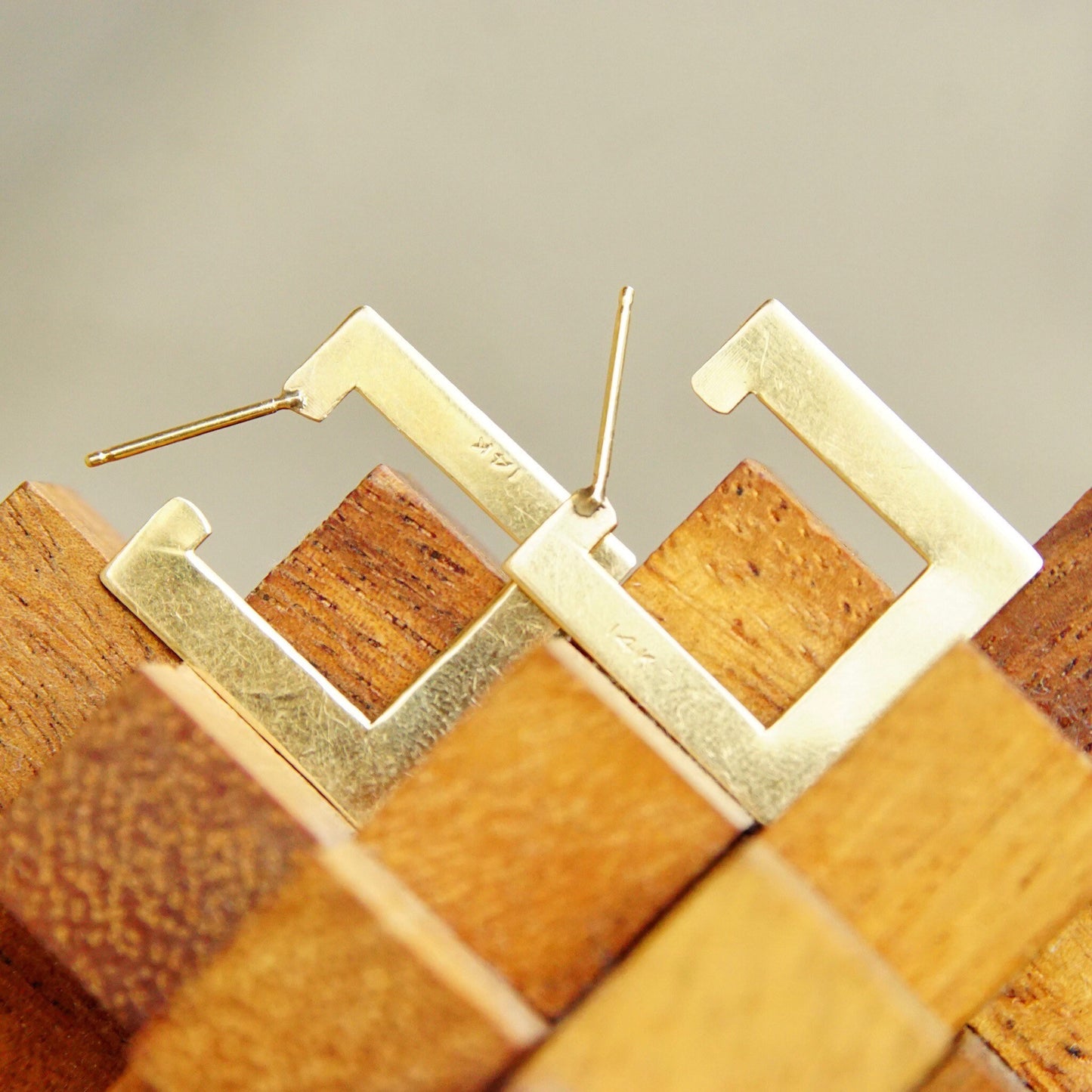 Minimalist 14K yellow gold square hoop earrings with geometric flat design, displaying sleek and sexy vintage style on wood surface.