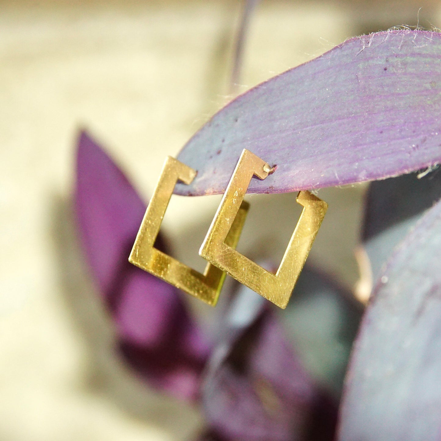 Vintage 14K yellow gold flat square geometric hoop earrings on purple leaves, minimalist sleek jewelry.