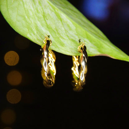 Vintage 14K yellow gold twisted hoop earrings featuring puffed repousse wreath design on leaf, small to medium size gold hoops measuring 17mm, classic 585 gold earrings against black background.