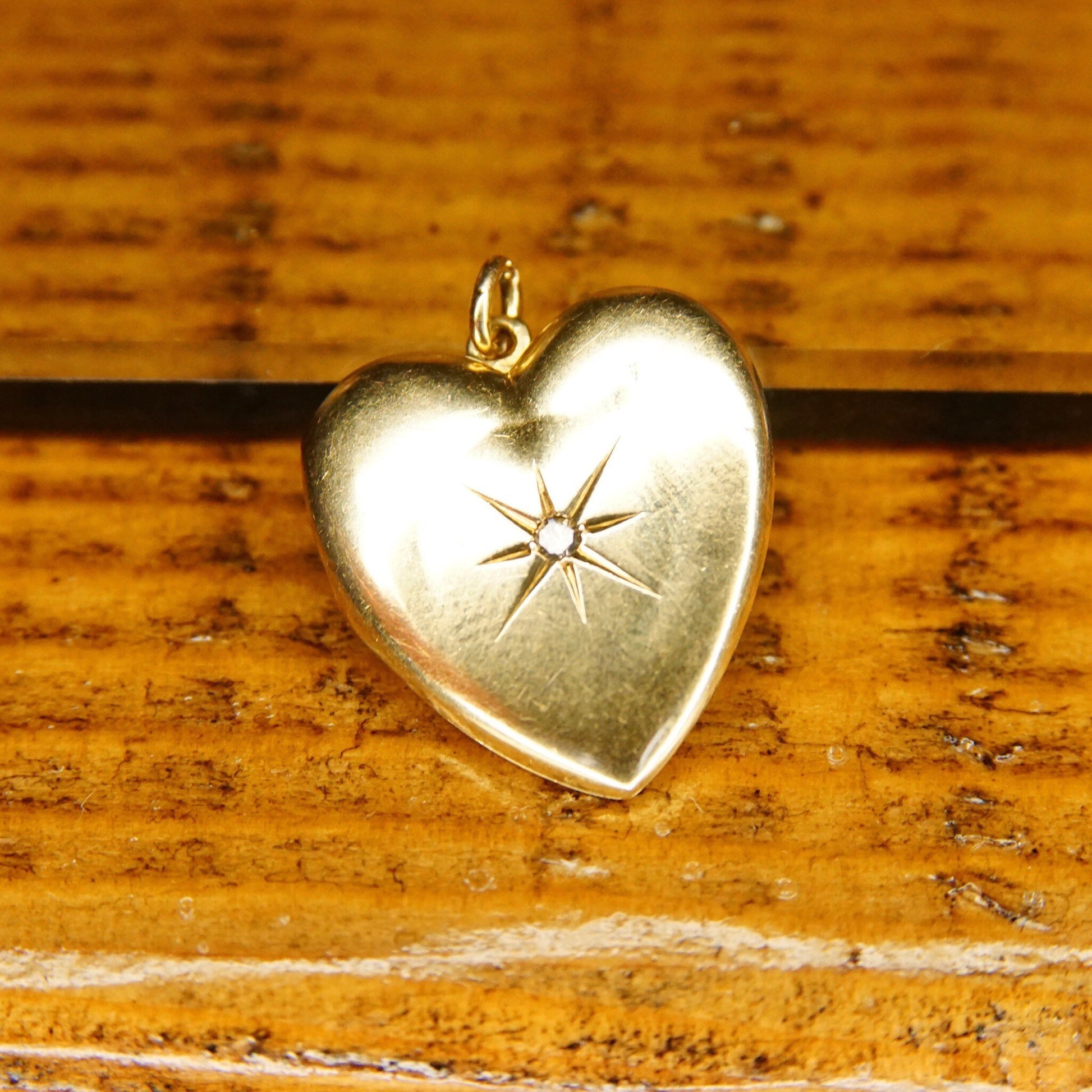 Antique 14K gold heart locket pendant with starburst design and mine cut diamond, featuring two frames for pictures, from the Victorian era mourning jewelry collection by EMESCO, measuring 1 inch in length.