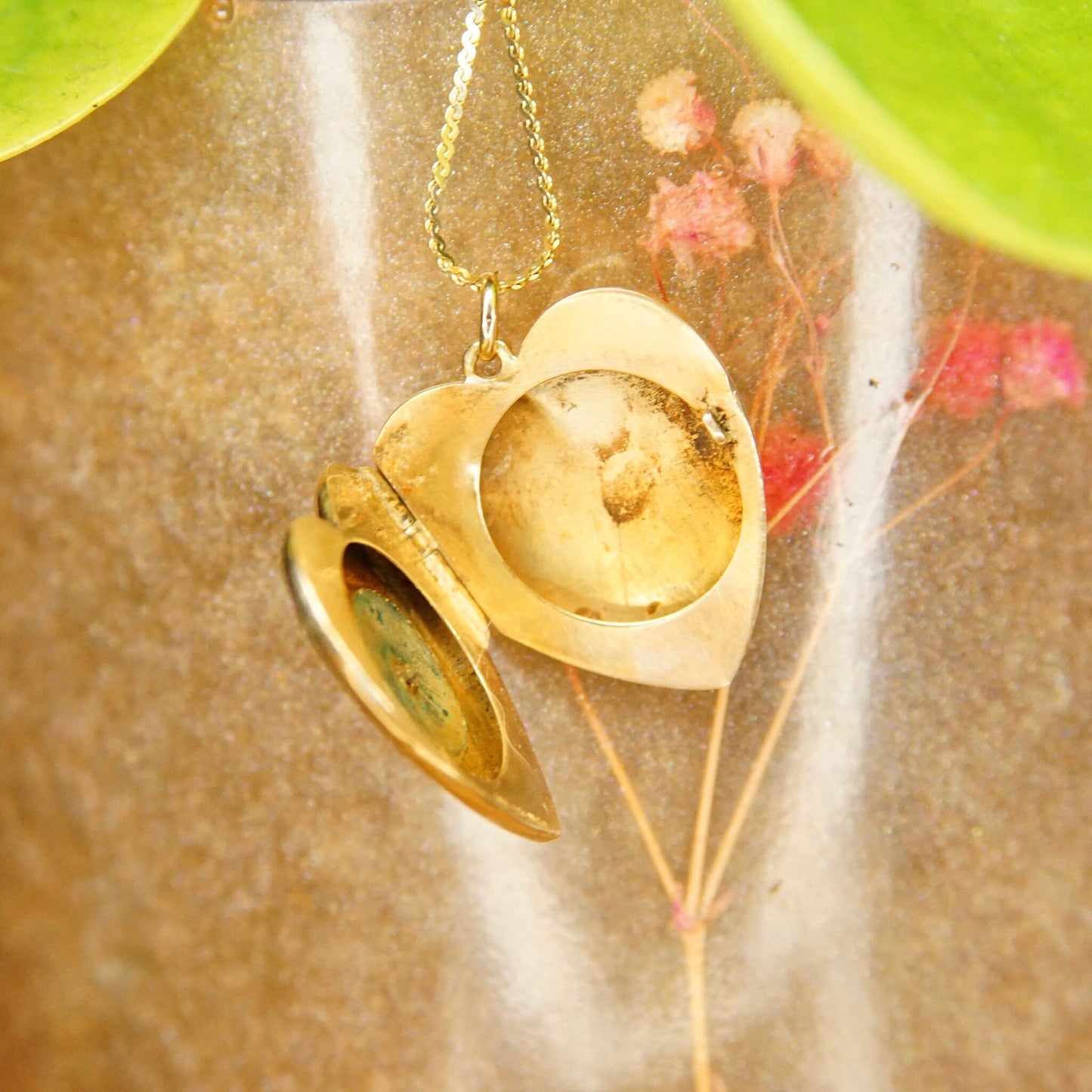 Antique 14K gold heart locket necklace with starburst design, featuring a small mine cut diamond in the center. The locket opens to reveal two frames for holding photos or mementos inside. The pendant hangs from a delicate gold chain. The piece exemplifies Victorian-era mourning jewelry.