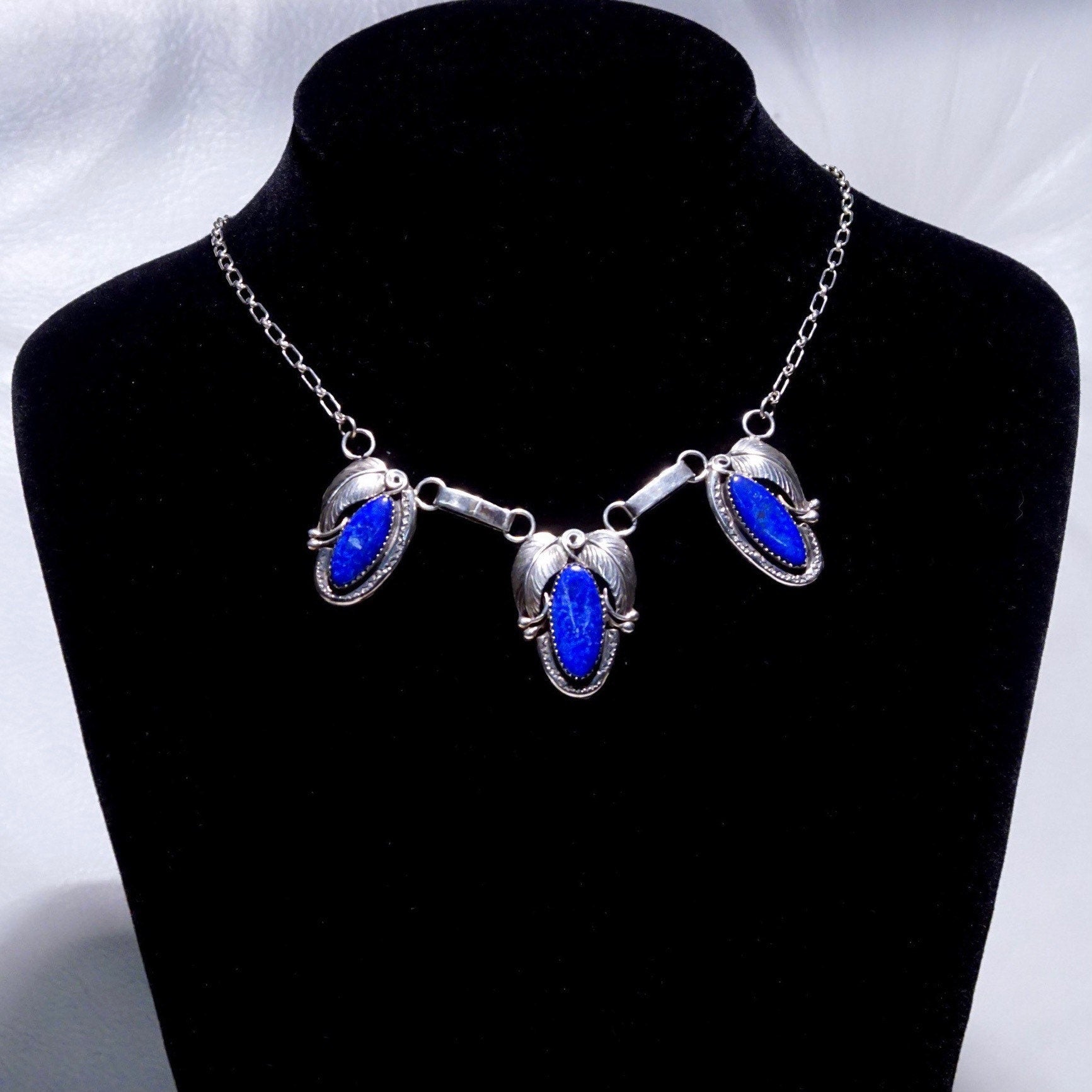 Vintage Native American sterling silver necklace featuring a 3-stone lapis lazuli pendant with engraved leaf settings on an oval link chain, measuring 20 3/4 inches in length.