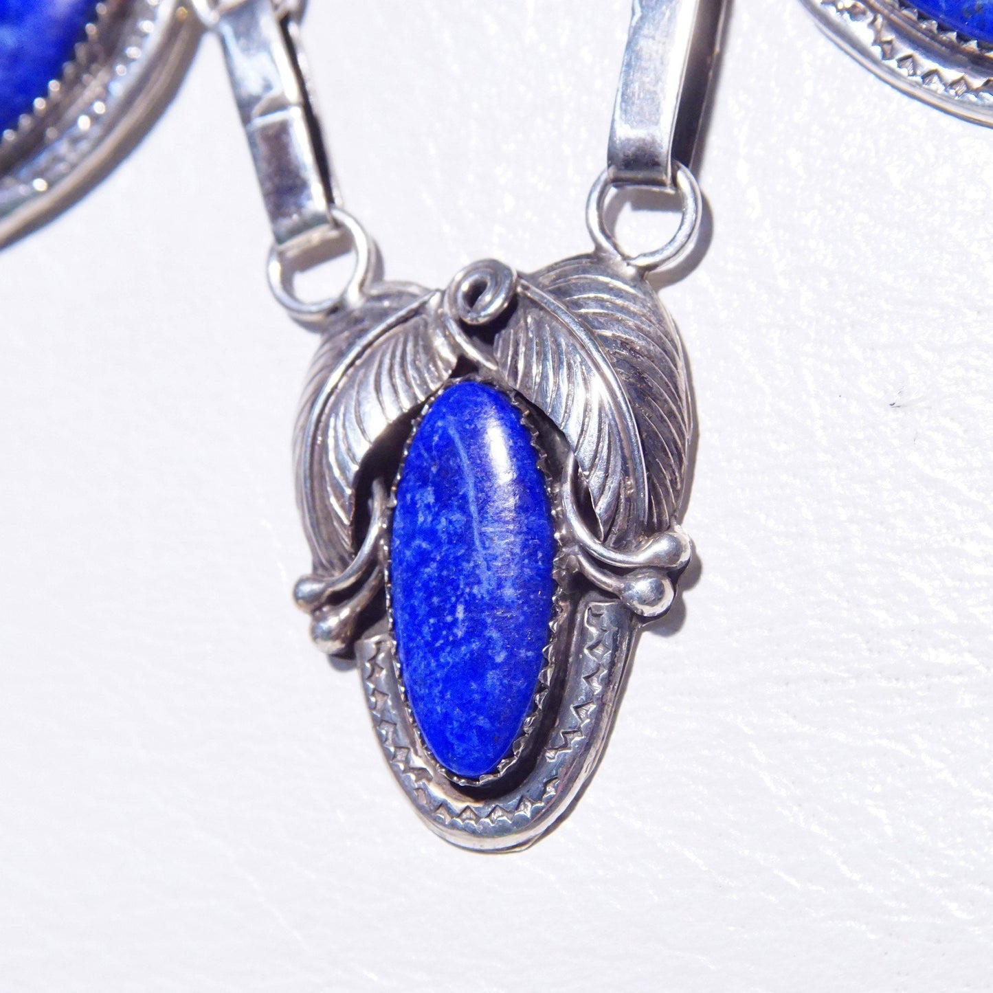 Vintage Native American sterling silver lapis lazuli pendant necklace featuring three oval lapis stones set in engraved leaf settings, suspended from an oval link chain measuring 20 3/4 inches long.