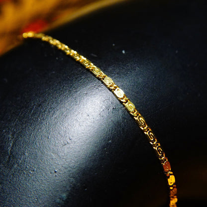 Vintage 14k yellow gold snail chain bracelet with delicate 1.5mm swirl links on dark surface, 6 1/2 inches long