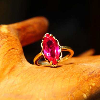 Antique 10K yellow gold marquise ruby ring featuring a faceted red gemstone on a straight gold band, size 6 1/4 US.