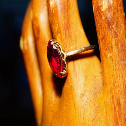 Antique 10K yellow gold marquise cut faceted ruby solitaire ring on wooden surface, size 6 1/4 US.