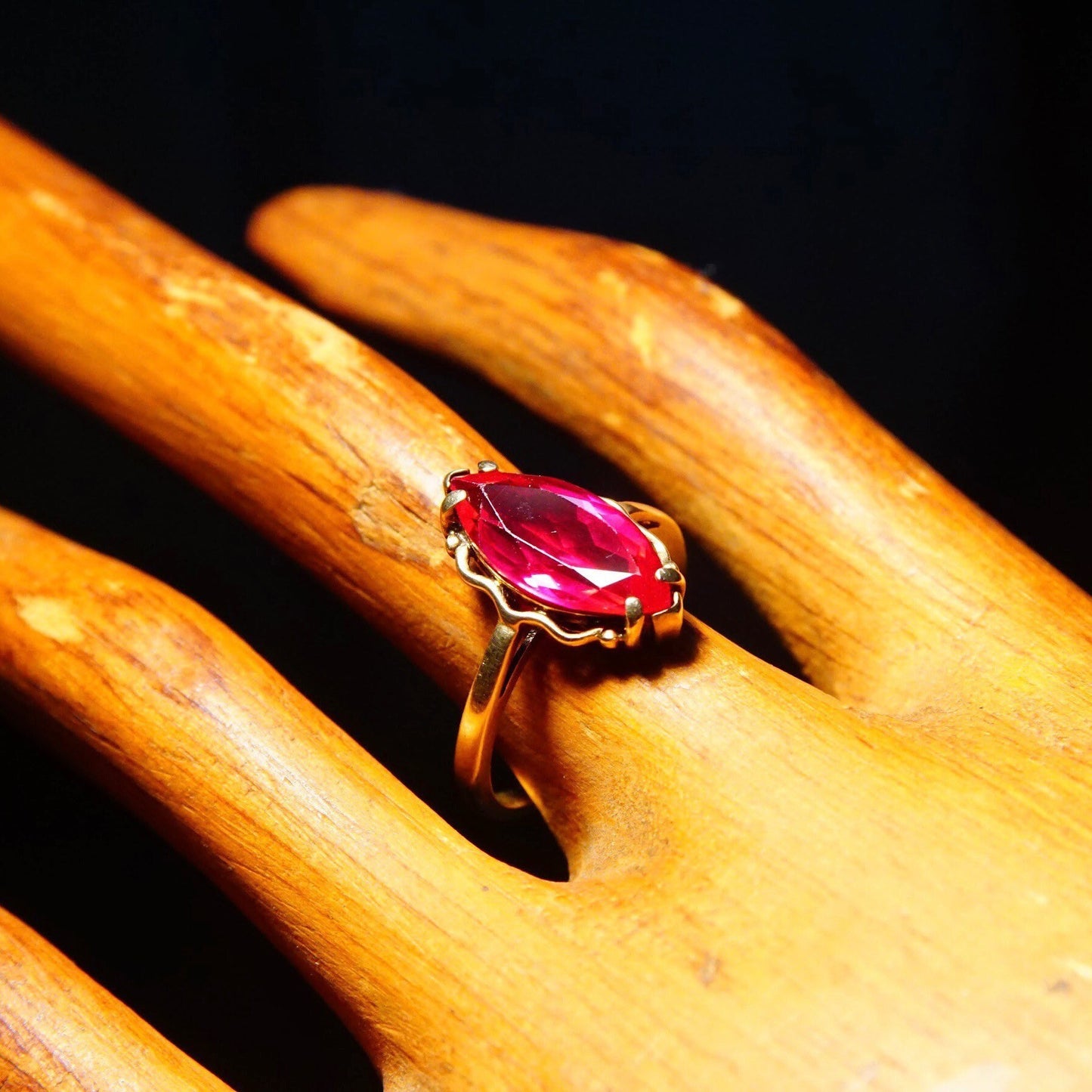 Red ruby ring on wooden surface, antique 10K yellow gold setting with marquise cut faceted gemstone, straight gold band, size 6 1/4 US