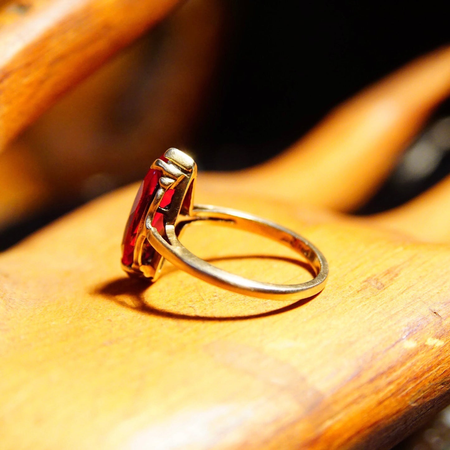 Antique 10K yellow gold marquise ruby ring with faceted red gemstone on a straight gold band, size 6 1/4 US, shown on a wooden surface.