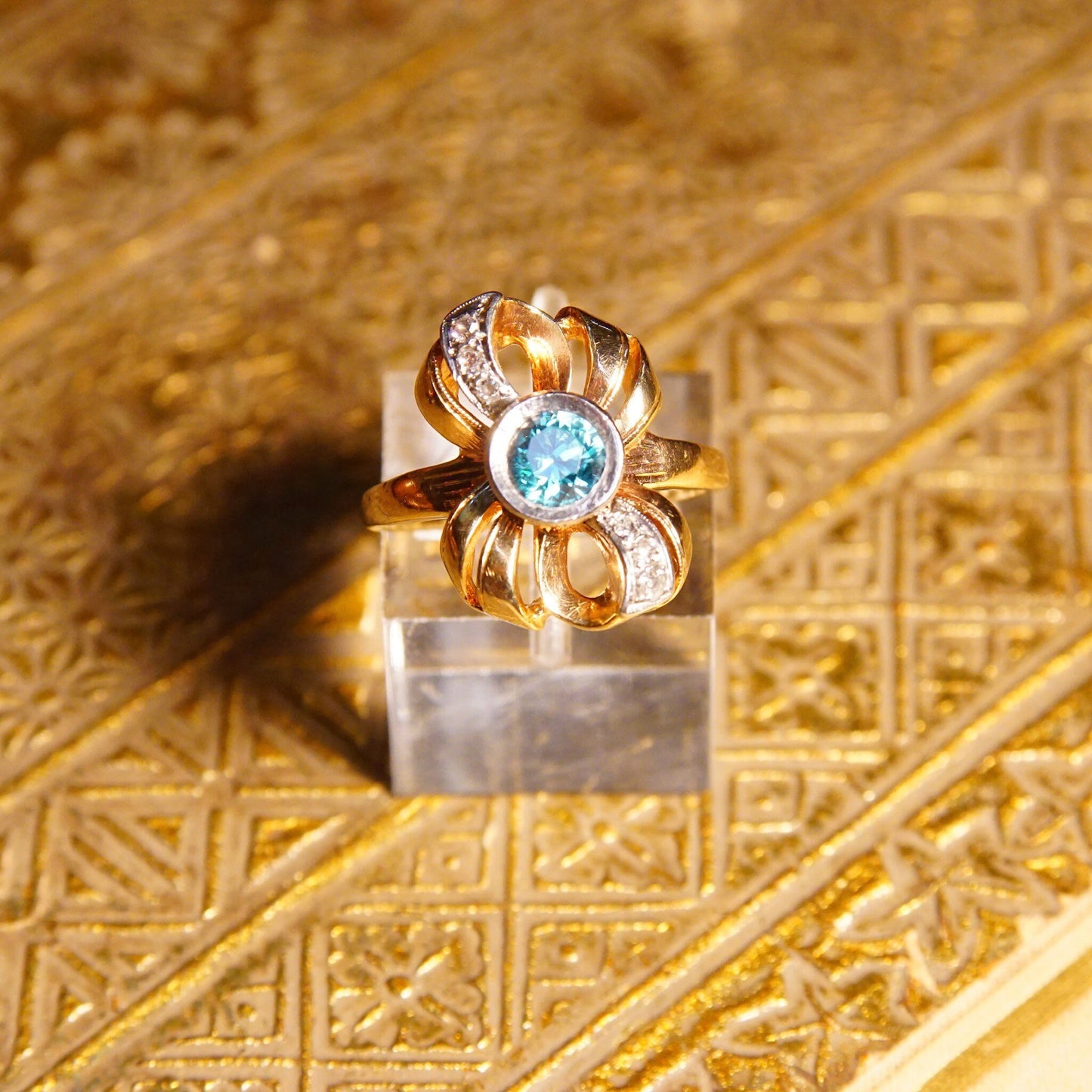 Antique 10K gold blue topaz and diamond bow ring featuring a brilliant blue gemstone in a ribbon setting with white gold accents, made by JR Woods & Sons, size 6 3/4 US.