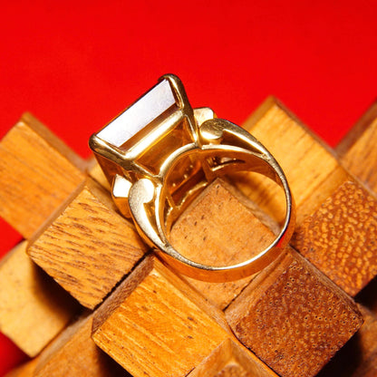 14K yellow gold cocktail ring with large emerald-cut citrine gemstone on geometric wooden block background