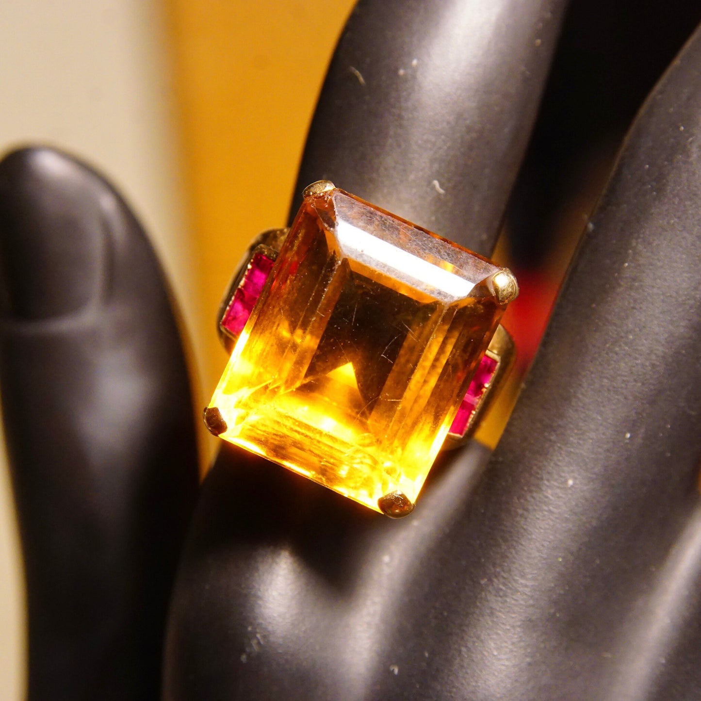 Striking 14K yellow gold estate cocktail ring featuring a large emerald-cut citrine gemstone accented with rubies on a black mannequin hand display.