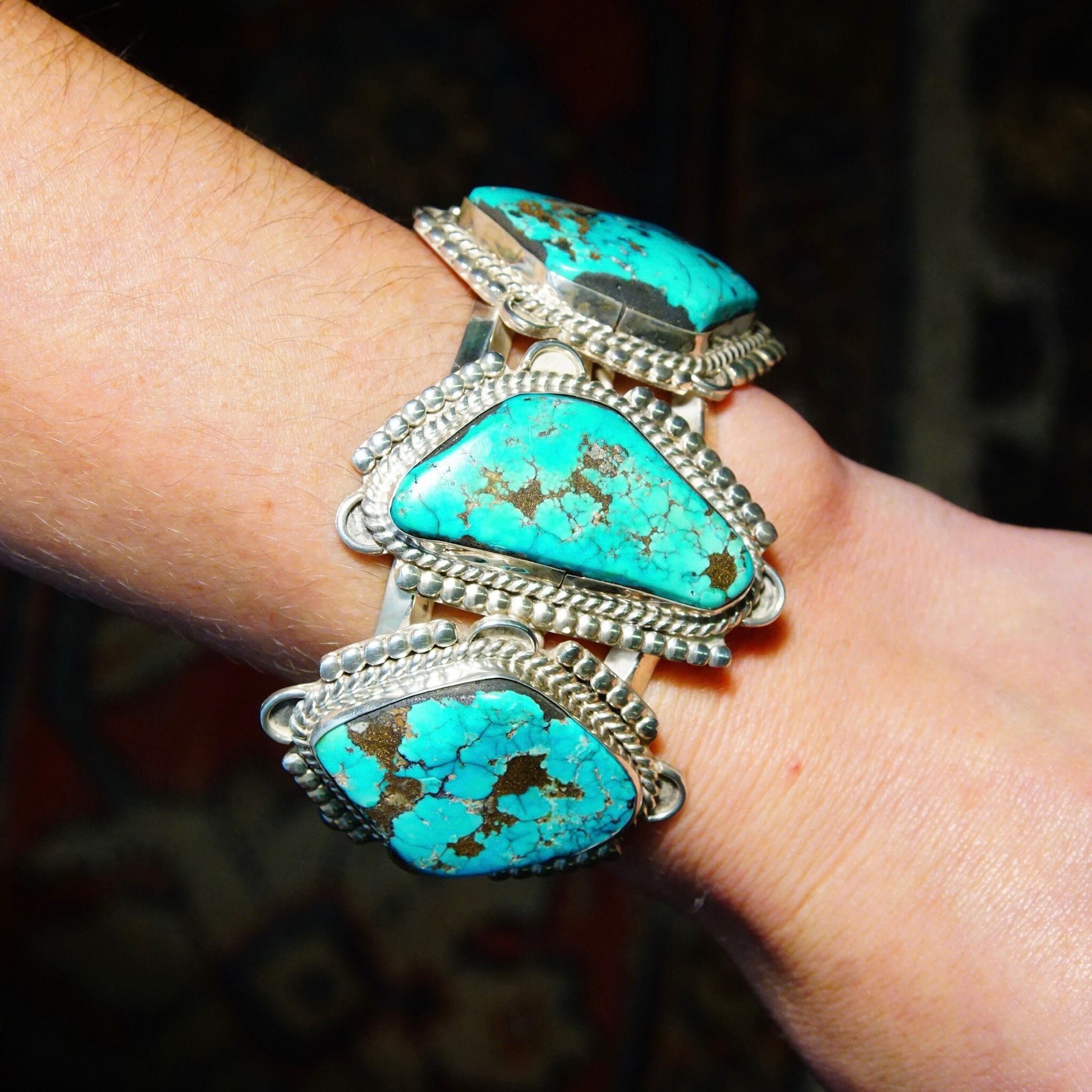 Vintage Native American turquoise cuff bracelet with chunky silver and three large turquoise stones, crafted in Mexico, measuring 5 3/4 inches long, shown on a person's wrist.