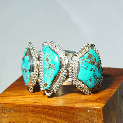 Vintage Native American silver cuff bracelet featuring three large turquoise stones, crafted in Mexico. The chunky silver bracelet measures 5 3/4 inches long and showcases vibrant blue-green turquoise cabochons set in detailed silver work.