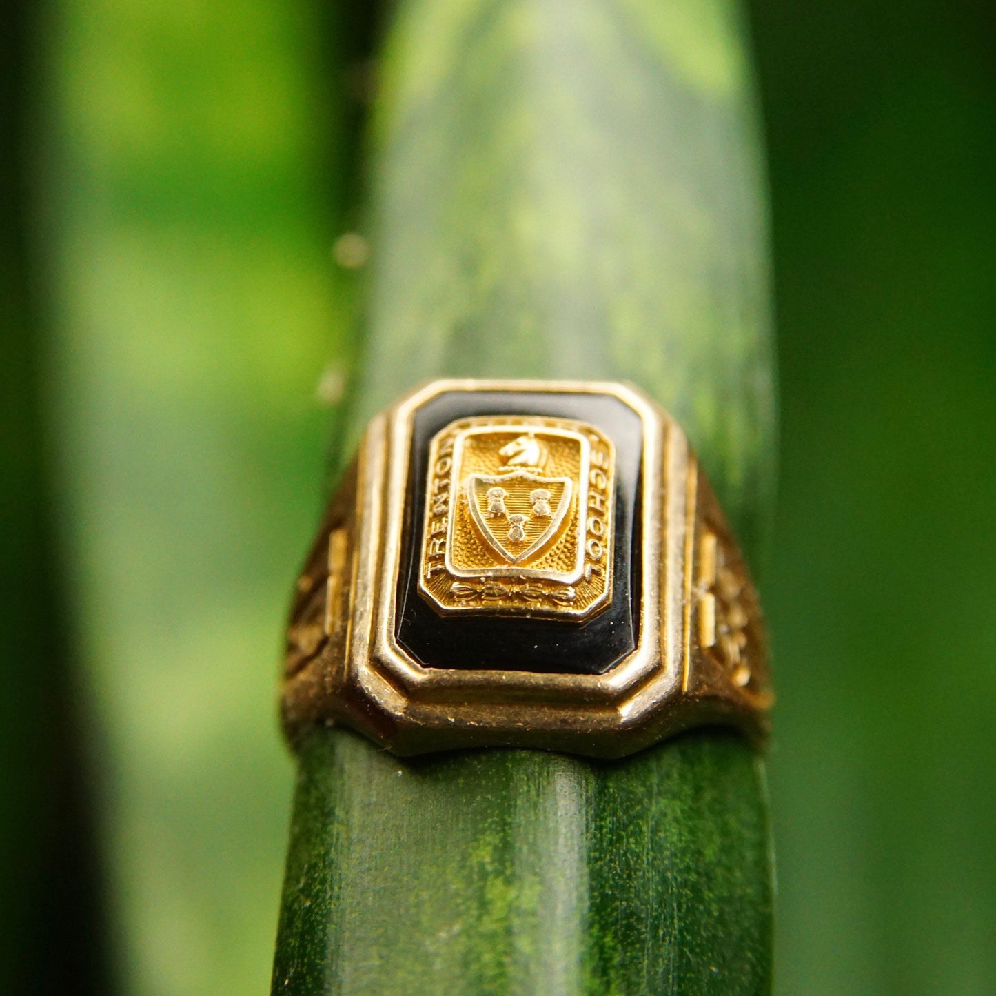 Vintage 1938 10K yellow gold Trenton High School class ring with onyx stone featuring engraved coat of arms, size 6 3/4 US, Murchison Ultra Supertone maker's mark, photographed on green wooden surface