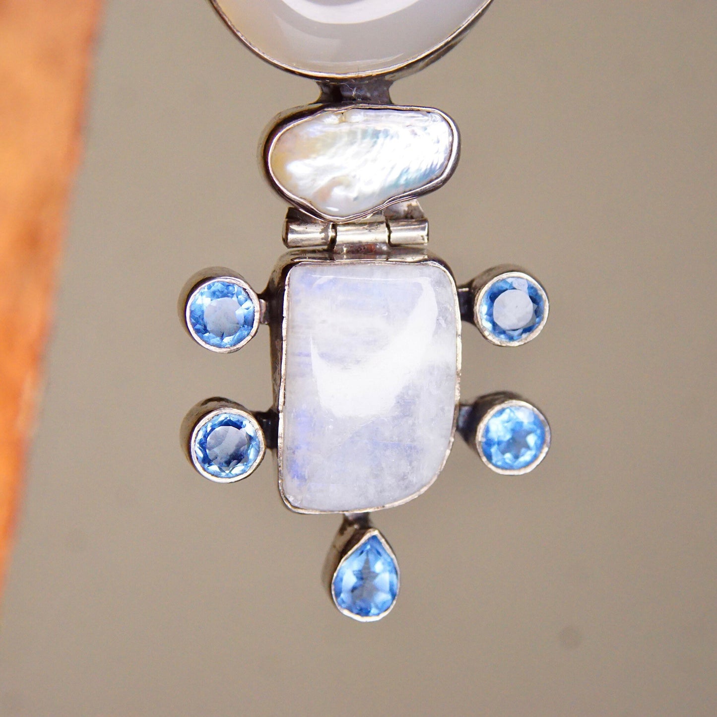 Vintage abstract modernist sterling silver pendant featuring moonstone, mother of pearl, quartz and blue gemstones in a hinged design, measuring 3 1/8 inches in length.