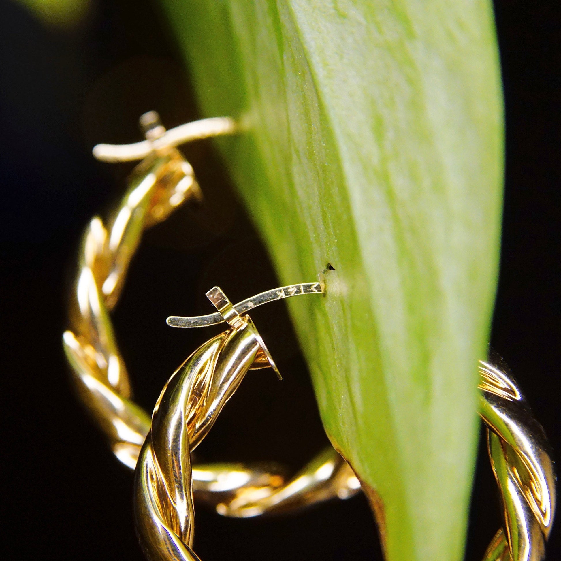 Vintage 14K yellow gold twisted hoop earrings with puffed repousse wreath design on green leaf background, classic 585 gold small to medium-sized hoops measuring 17mm in diameter.