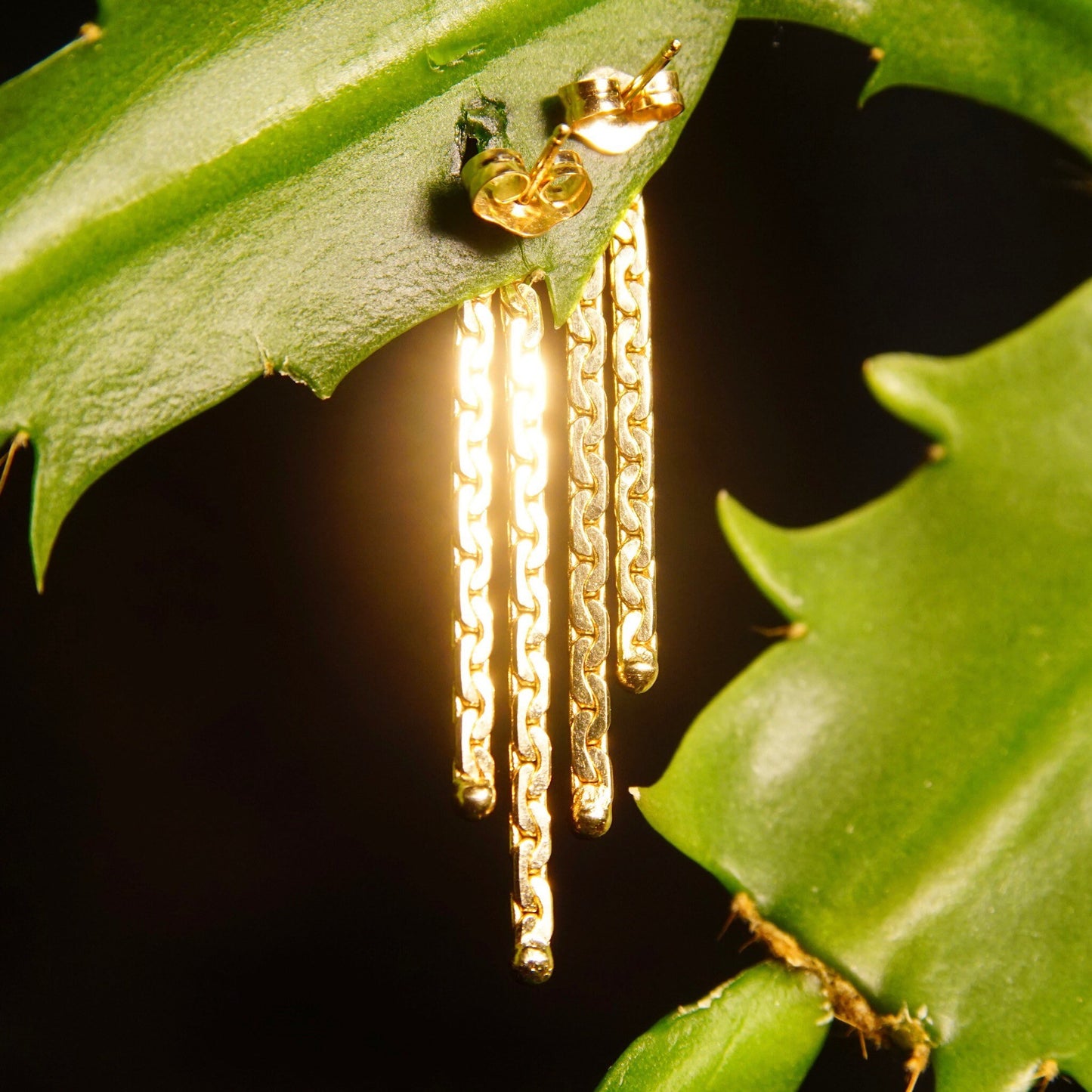 Vintage 14K gold tassel earrings with double strand Virola chains, half anchor links, and push back closures dangling from green leaves, measuring 1 3/8 inches long.