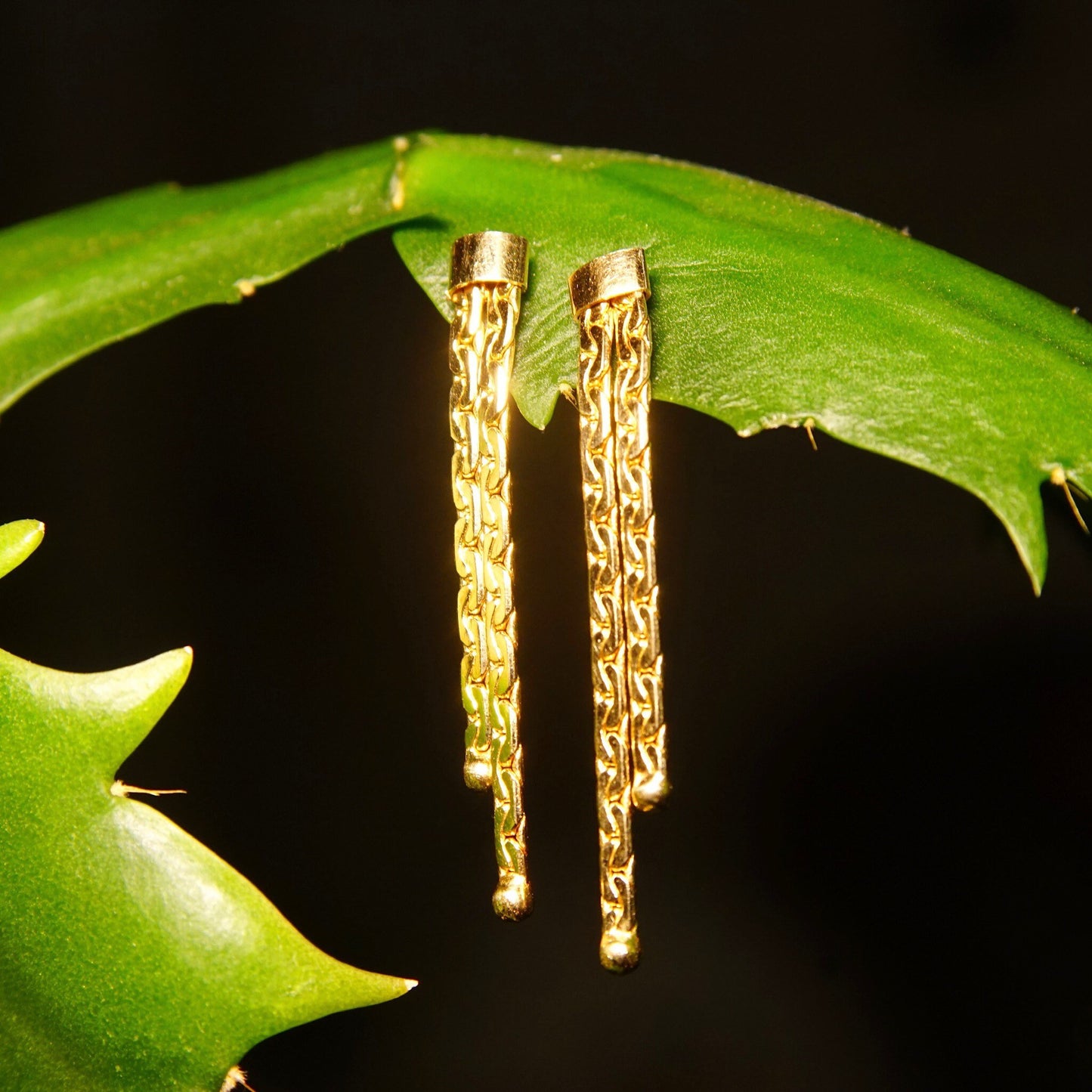 Vintage 14K gold chain tassel dangle earrings with push backs on leaf, closeup view showing intricate half anchor link chains against black background.