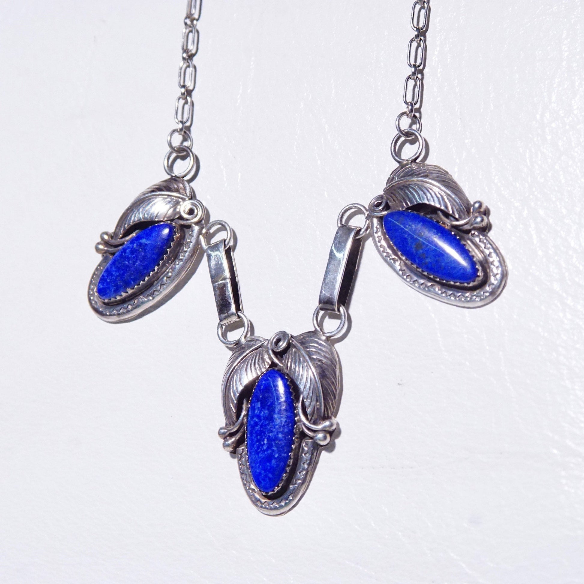 Vintage Native American sterling silver necklace with three oval lapis lazuli stones in engraved leaf settings on an oval link chain, measuring 20 3/4 inches long.