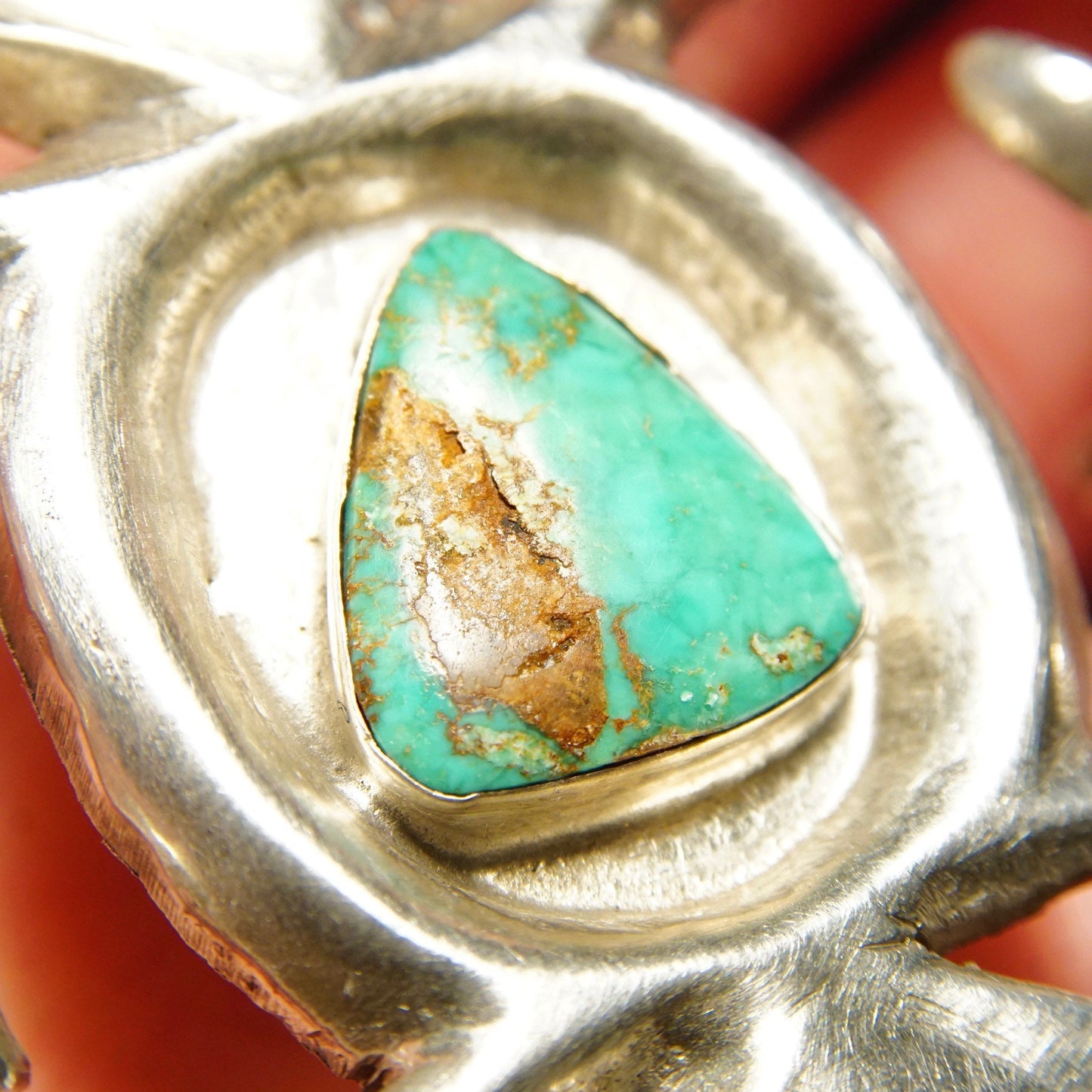 Vintage signed 'Phillip' Native American sterling silver and natural turquoise sand cast belt buckle, measuring 3 1/8 inches wide, featuring a triangular piece of turquoise with brown matrix set in an organically shaped silver bezel with a brushed, textured silver background.
